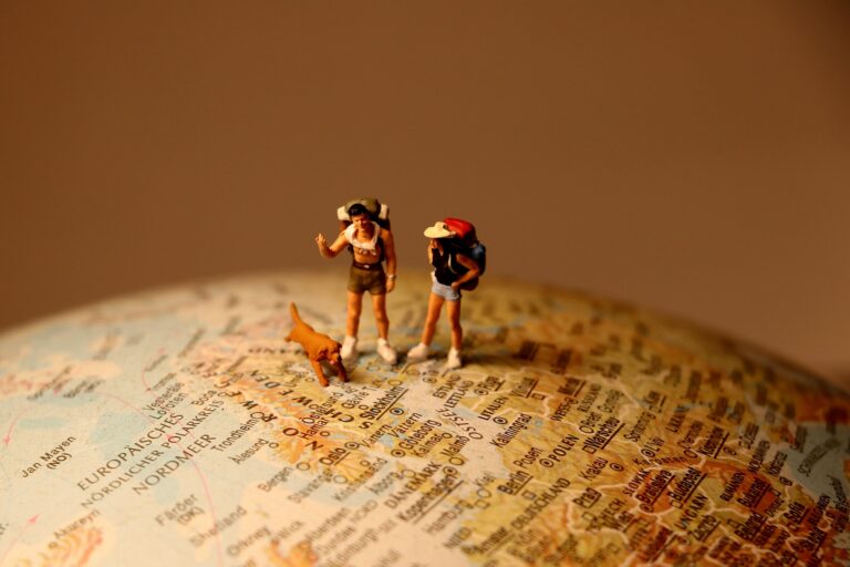 Miniature hikers with dog standing on world map travel concept