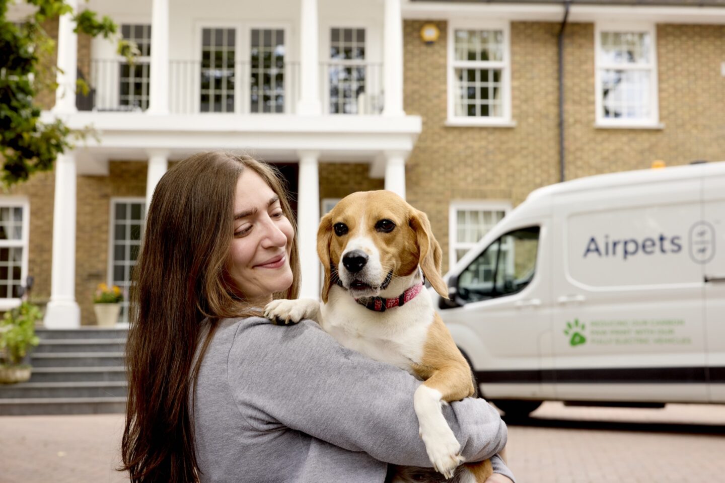 Woman holding a beagle beside Airpets van